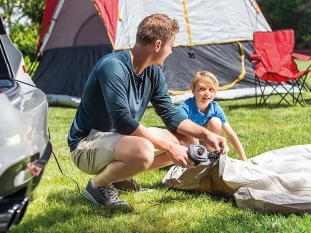 Twee personen maken gebruik van de elektrische pomp om een luchtbed op te blazen.