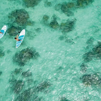 Twee personen paddleboarden over helder turquoise water met donkere onderwaterrotsen en glijden soepel op de Intex AquaQuest 320 SUP-set van Intex, gebouwd met Drop Stitch-technologie voor uitstekende stabiliteit.