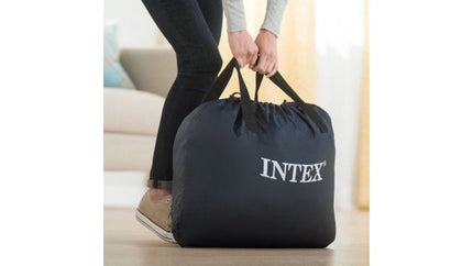 Vrouw tilt de Intex draagtas van het Ultra Plush luchtbed in huis