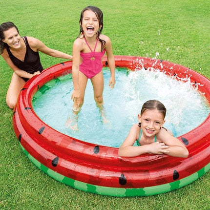 Moeder en kinderen spelen in het Intex watermeloen zwembad in de tuin
